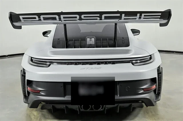 Dead-on rear view: full-width light bar, centre-exit tailpipes, PORSCHE wing lettering